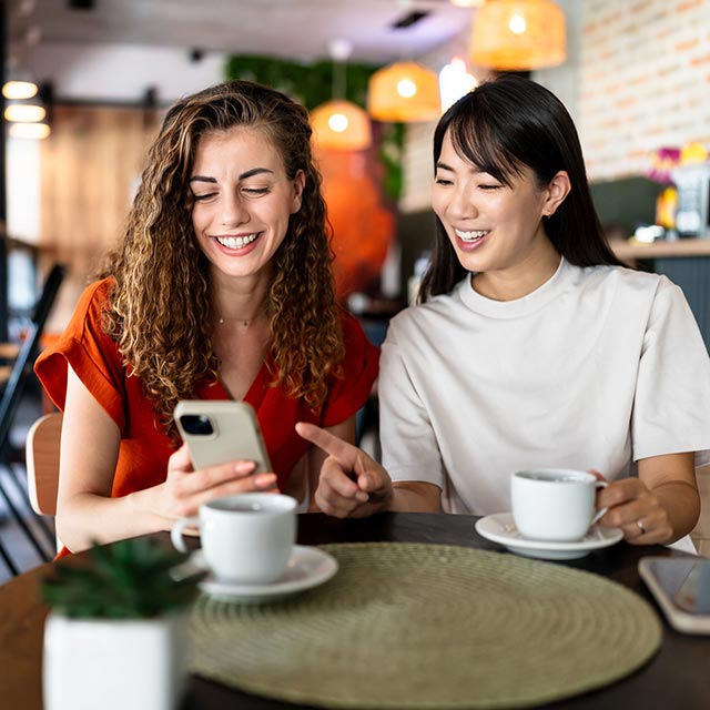 Friends looking at a phone at a coffee shop