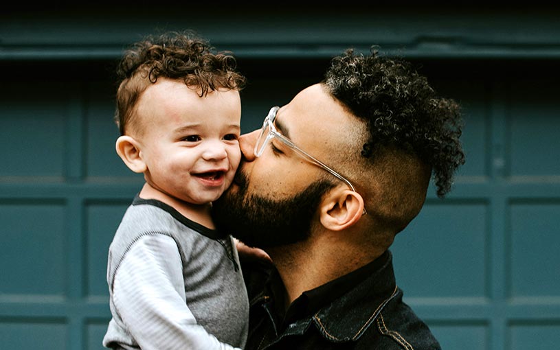 Father holding son in front of garage door.